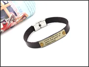Detail eines Vintage-Lederarmbands mit graviertem Zitat auf einer Metallplatte