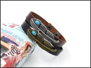 Detail von Lederarmbändern mit Türkis-Federanhängern und verstellbaren Druckknöpfen