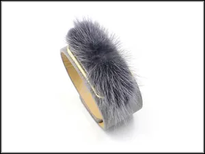 Macro detail of wide grey leather cuff bracelet with faux fur trim and gold metal border