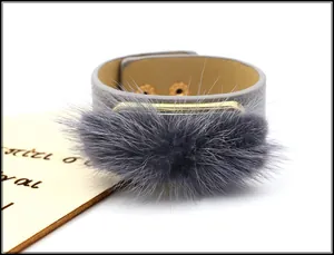Detail of gray leather cuff bracelet featuring fluffy fur trim and gold metal accent