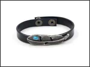 Detailaufnahme von Lederarmband mit Metallfeder und türkisfarbenem Stein im Vintage-Stil