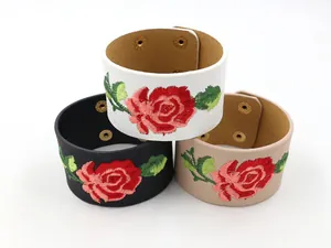 Détail de trois bracelets larges en cuir PU avec roses brodées et boutons-pression dorés