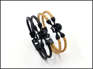 Makroaufnahme von schwarzen Totenkopf-Ornamenten und geflochtenen Lederarmbändern im Punk