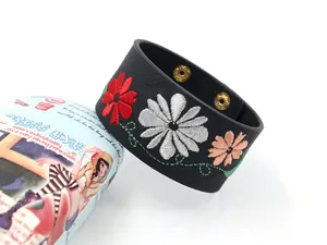 Detailed macro view of multi-color flower embroidery on black PU leather wide bracelet
