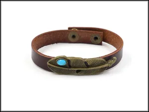 Detail eines Vintage-Lederarmbands mit Bronze-Feder und türkisfarbenem Steinbesatz