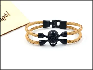 Detail eines hellbraun geflochtenen Lederarmbands mit mattem schwarzem Totenkopf-Element