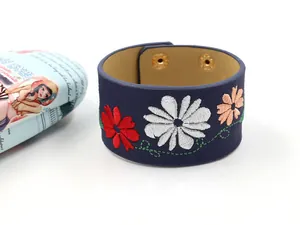 Detailed close-up of dark blue PU leather wide bracelet with floral embroidery and gold snaps