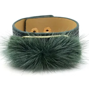 Wide dark green leather bracelet with faux fur pom-pom and gold metal snap buttons