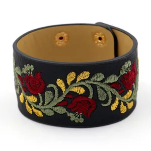 Brazalete ancho de cuero negro con bordado floral colorido y botones de presión dorados