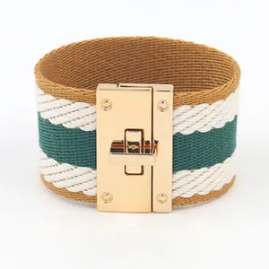 Detail van brede geweven armband met groen-witte strepen en gouden metalen draaisluiting