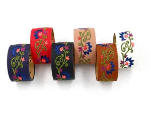 Detalle de bordado floral en pulseras anchas de cuero PU multicolor con cierres dorados