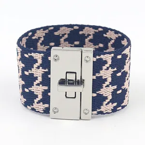 Detail van brede geweven armband met pied-de-poule patroon en zilveren draaisluiting