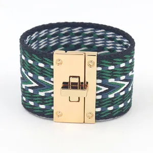 Detailopname van de geweven textuur en de goudkleurige draaisluiting op de armband