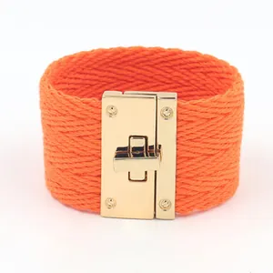 Detail van oranje geweven band met goudkleurige draaisluiting op een brede armband