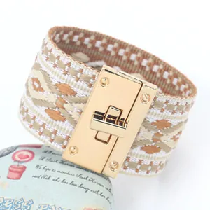 Detail van geweven geometrische brede armband met gouden rechthoekige draaisluiting