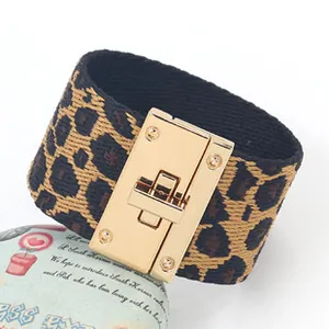 Detail van luipaardprint stoffen armband met grote gepolijste gouden metalen sluiting