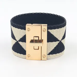 Detailopname van een brede geweven armband met een goudkleurige draaisluiting gesp