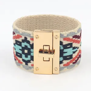 Detail van een brede stoffen boho armband met borduursels en gouden draaisluiting