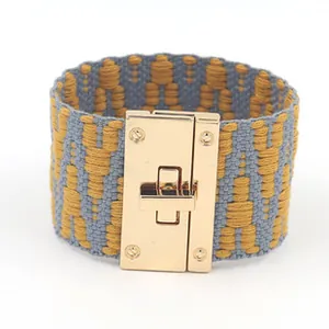 Detailweergave van de brede geweven armband met grijs-geel patroon en gouden slot