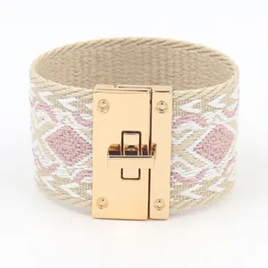 Detail van een roze geweven armband met geometrisch patroon en goudkleurige sluiting