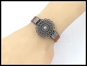 Macro detail of brown leather bracelet featuring a large silver carved mandala ornament