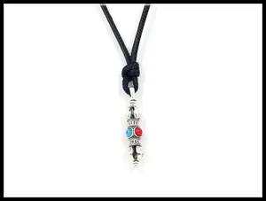 Detailed view of an antique silver Vajra pendant with red and blue turquoise stones