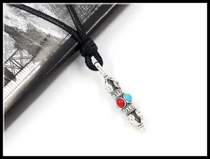 Detailed close-up of a Tibetan silver Vajra pendant with red and blue inset beads