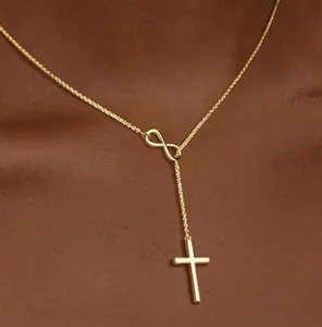 Detail of 18K gold Y-necklace featuring infinity symbol and cubic zirconia cross pendant