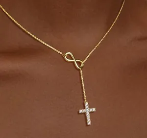 Macro shot of 18K gold infinity symbol and cubic zirconia cross pendant on gold chain