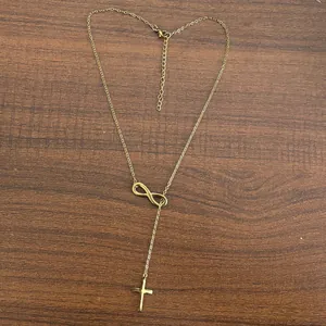 Detail of 18K gold infinity symbol and cross pendant on a delicate Y-lariat chain
