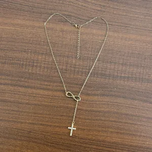 Close-up of 18K gold infinity necklace with micro-paved CZ zircon cross pendant