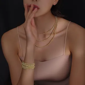 Detalle de elegante collar de tres capas y pulsera de múltiples hilos en oro de 18k