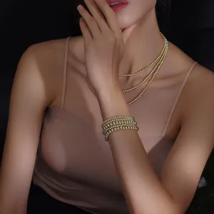 Detail showing five-layer stacked 18K gold-plated beaded bracelets on female model wrist