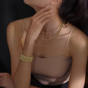 Detail of high-polish gold bead multi-layer necklace and bracelet set on model