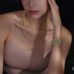 Close-up of layered 18K gold stainless steel bead necklaces and bracelets on model