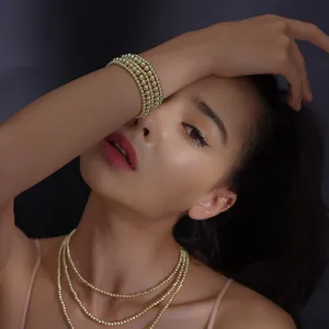 Conjunto de pulsera y collar de cuentas bañadas en oro de 18K usado por una modelo en detalle