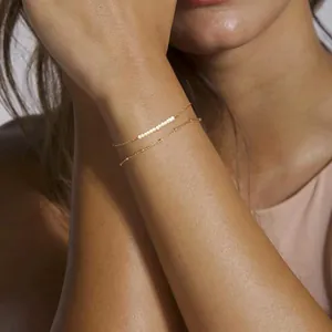 Close-up of double-layer gold chain bracelet with baroque pearls on model wrist