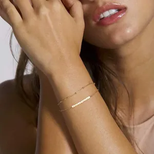 Double-layered 18K gold plated stainless steel bracelet with baroque pearls on a wrist