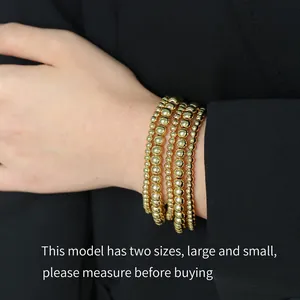 Detail of 18K gold beaded stretch bracelets in large and small sizes on wrist