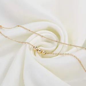 Detailed shot of 18K gold plated beaded chain with polished beads on white silk background