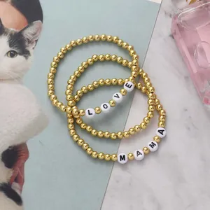 Detailed macro view of 18K gold beaded elastic bracelets featuring LOVE and MAMA lettering