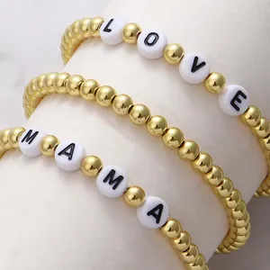 Macro detail of 18K gold beaded stretch bracelets with LOVE and MAMA letter beads