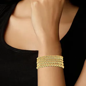 Close-up of a five-layer gold beaded bracelet featuring a textured evil eye design