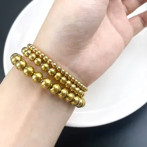 Close-up of a three-piece set of polished gold beaded elastic bracelets worn on the wrist