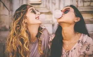 Two women wearing gold double-layer letter necklaces in a casual lifestyle scene