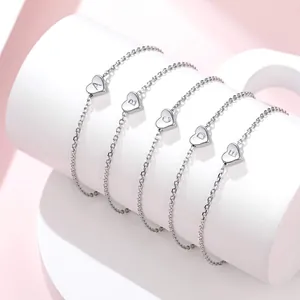 Detail of five silver chain bracelets with heart-shaped initial charms A to E