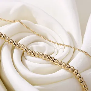 Macro detail of a 18K gold-plated double-layer beaded bracelet set on white silk fabric