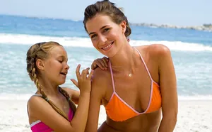 Detail of 18K gold letter B pendant necklace on a model wearing an orange bikini
