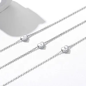 Close-up of heart-shaped charms with engraved letters O, F, A on stainless steel bracelets