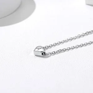 Close-up of heart-shaped stainless steel pendant with letter A on a delicate silver chain